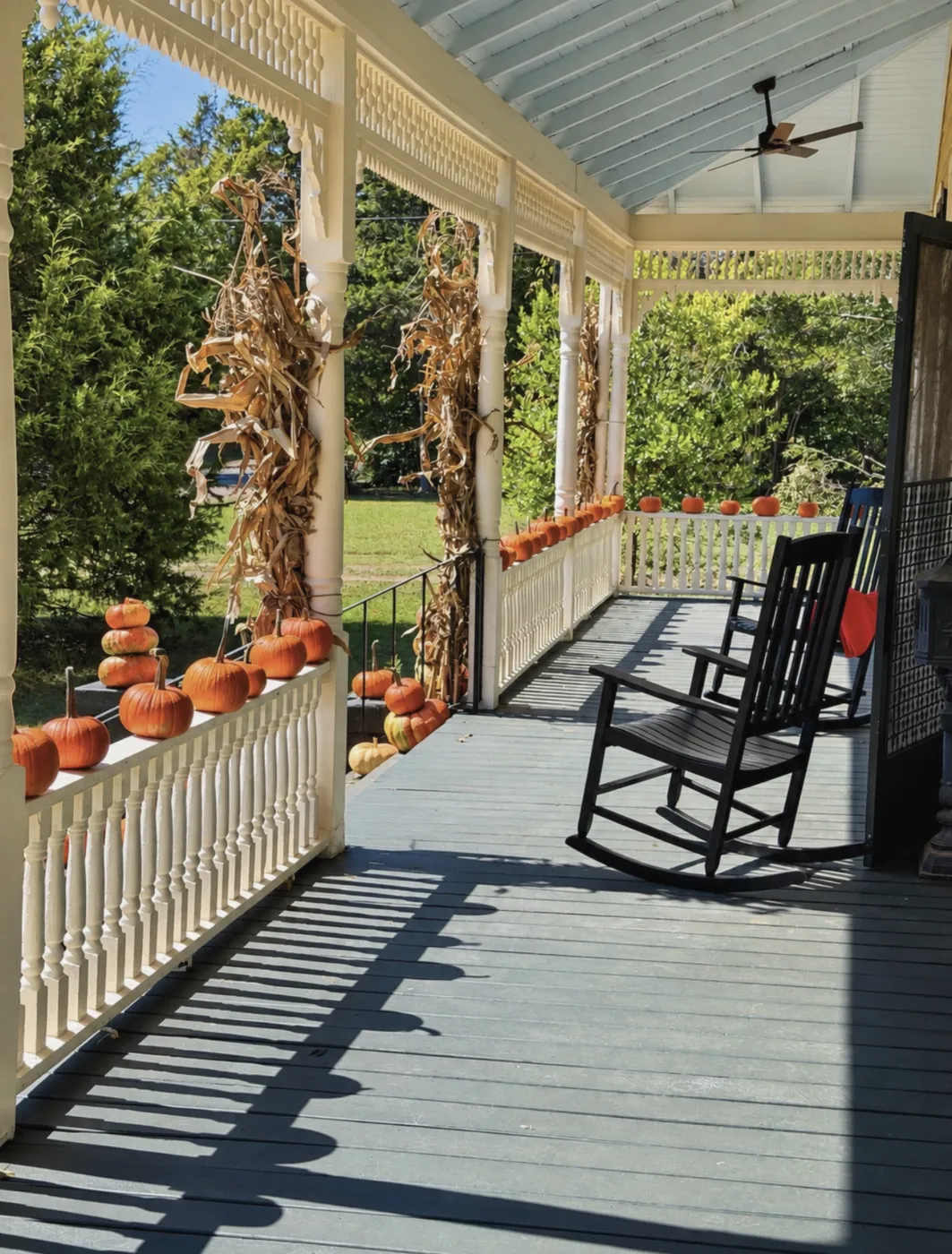 VanCleave Hall's wraparound porch with black rocking chairs, white spindle railing and turned columns, a backdrop for engagement photos