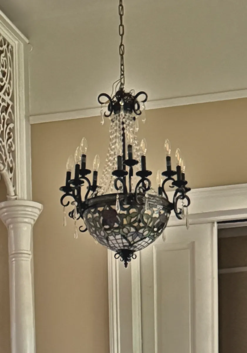 Wrought-iron and crystal chandelier in the entry hall beside the fretwork columns