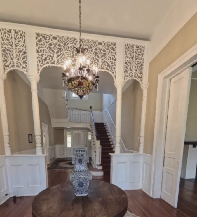 Entry hall with a white fretwork screen and a stained-glass chandelier above the staircase