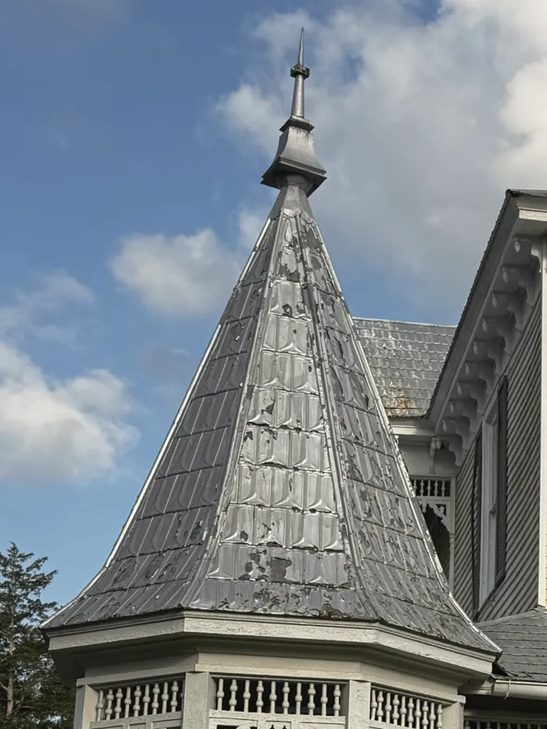 The pressed-tin spire and finial of the octagonal turret against a blue sky